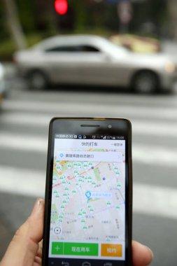 A Chinese mobile phone user uses taxi-hailing app Kuaidi Dache on his smartphone on a road in Shanghai, China, 15 February 2015 clipart
