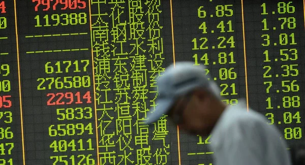 2015年8月21日 在中国东部浙江省杭州市一家股票经纪公司 一位关心此事的中国投资者走过一个屏幕 显示股价 价格上涨为红色 价格下跌为绿色 — 图库照片