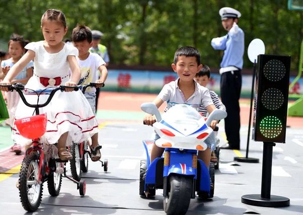 警察官ハクケン市 中国東部の安徽省 2015 日シハク村の中央小学校でのセッションを学ぶ交通ルール中に模擬道路で自転車とグッズ三輪車に乗る若い学生に指示します — ストック写真