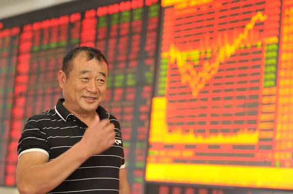 2015年6月17日 在中国东部安徽省阜阳市一家股票经纪公司 一位中国投资者在屏幕前微笑着展示上证综指和股价 价格上涨为红色 价格下跌为绿色 — 图库照片