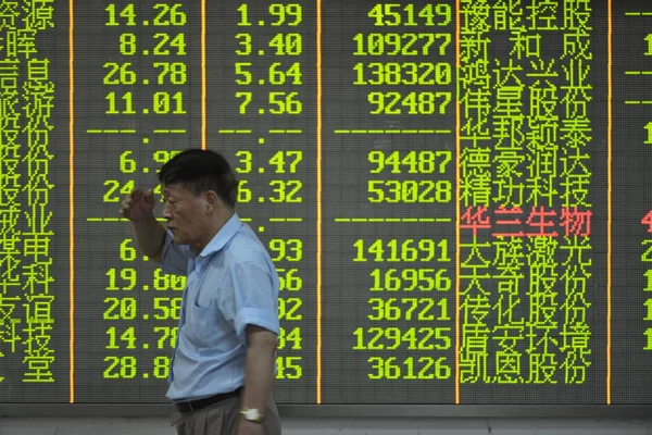 2015年8月3日 在中国东部浙江省杭州市一家股票经纪公司 一位中国投资者走过一个显示股价 价格上涨为红色 价格下跌为绿色 的屏幕 — 图库照片