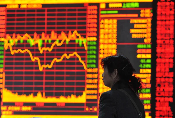 中国の投資家は 2015 日中国東部の安徽省阜陽市の株式証券会社で株価指数を表示する画面を過ぎて歩く — ストック写真