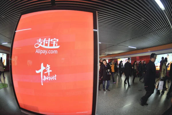 歩行者は 中国の上海の地下鉄駅でアリババグループのアリペイモバイル決済サービスの広告を通り過ぎる 2014年12月8日 — ストック写真
