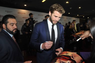 Australian actor Liam Hemsworth, center, signs autographs for fans at a premiere for his movie 