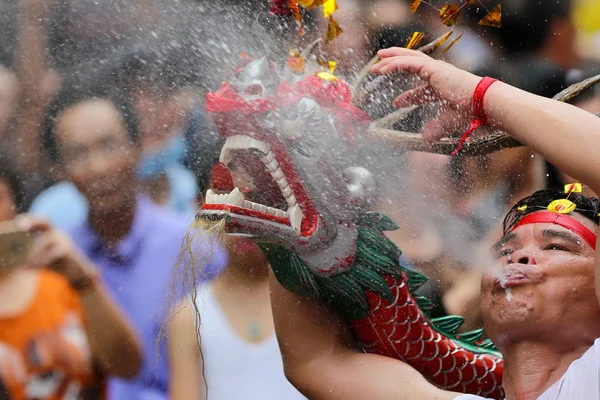 実行者は 2015 日中国 マカオでお釈迦様の誕生日を祝うために酒に酔ったドラゴン祭り中に酒に酔ったドラゴン ダンスを実行する彼の口からビールをスプレーします — ストック写真