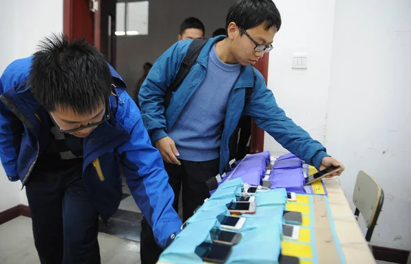 学生は彼らのスマート フォンを入れて太原理工大学 2015 日北中国の山西省太原市で携帯電話の無料教室のクラスの先頭に指定したストレージ バッグ — ストック写真