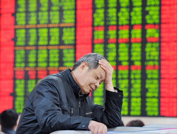 2015 日中国東部の安徽省阜陽市の証券会社の家で 赤の価格上昇 と価格下落のため緑の株式の価格を見て懸念している中国語の投資家 — ストック写真