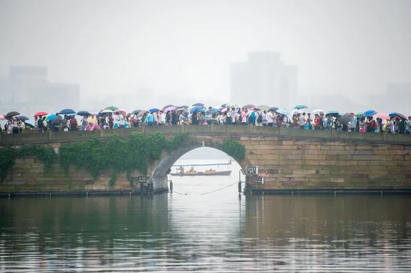 2015年10月4日 在中国东部浙江省杭州市的雨中 拿着雨伞的游客在西湖断桥上散步 — 图库照片