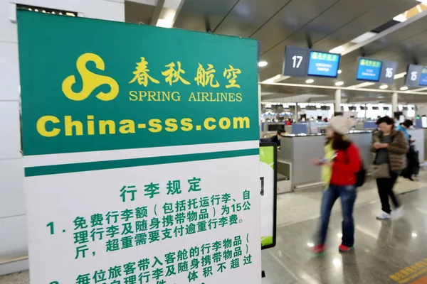 乗客は 2015 日中国 上海市に上海浦東国際空港に春秋航空のポスターを歩く — ストック写真