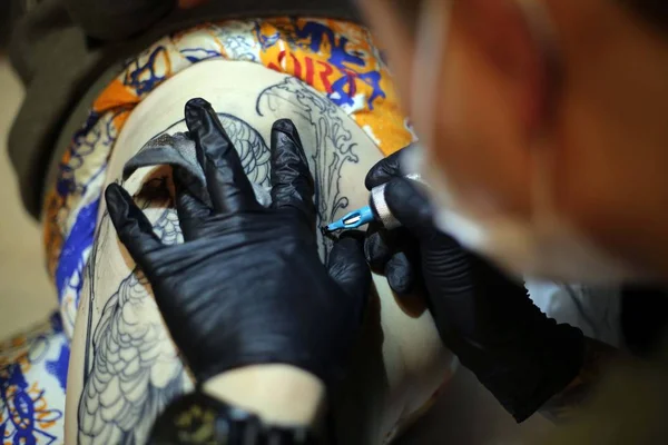 中国纹身艺术家王文斌在中国上海一家纹身工作室的顾客大腿上眨眼 2015年3月29日 — 图库照片