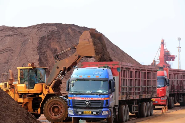 ホイールローダーは 中国東部の山東省Rizhao市のRizhao港で鉄鉱石を搭載したトラックを積み込みます 2015年6月27日 — ストック写真