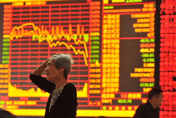 在中国东部安徽省阜阳市一家股票经纪公司 一名中国投资者在显示上证综指的屏幕前显得很担心 — 图库照片