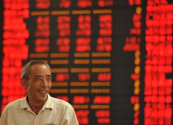 Chinese Investor Smiles Front Screen Displaying Prices Shares Red Price — стокове фото