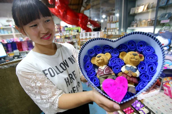 中国のセールスガールは 2015年8月18日 中国河南省海風市の工芸品店で 中国のバレンタインデーとしても知られる 今後のQixiフェスティバルのためにおもちゃのクマで飾られたバラの箱を示しています — ストック写真