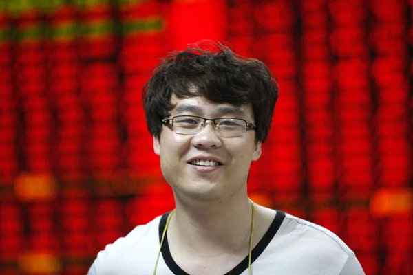 Китайский Инвестор Улыбается Перед Экраном Показывающим Цены Акции Красный Роста — стоковое фото