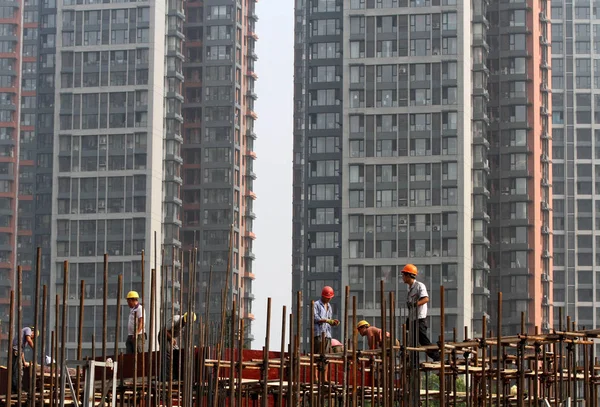 中国の出稼ぎ労働者は中国東部の江蘇省 2015 日安市居住用不動産プロジェクトの建設現場での足場を構築します — ストック写真