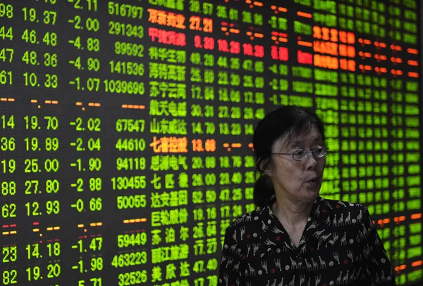 2015年8月20日 在中国东部浙江省杭州市一家股票经纪公司 一位关心此事的中国投资者走过显示股价 价格上涨为红色 价格下跌为绿色 的屏幕 — 图库照片