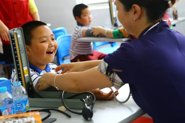 中国の労働者は 上海の学校で身体検査中に肥満の若い学生の血圧を測定します 2014 — ストック写真