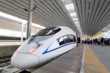 Passengers exit a CRH (China Railway High-speed) bullet train on the Shendan (Shenyang-Dandong) High-speed Railway at a railway station in Shenyang city, northeast China's Liaoning province, 1 September 2015 clipart