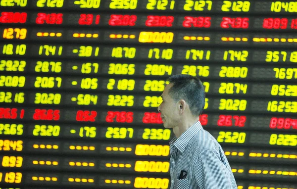 2015年5月28日 在中国东部安徽省淮北市的一家股票经纪公司 一位中国投资者走过一个显示股价 价格上涨为红色 价格下跌为绿色 的屏幕 — 图库照片