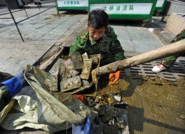 2015年4月27日 中国工人在中国中部湖北省武汉市武汉火车站的一个污水坑里收集他们找到的手机 — 图库照片