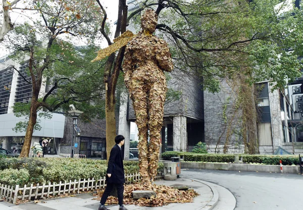 2015年12月14日 在中国东部浙江省杭州市中国艺术研究院门前 一位行人走过一幅由落叶制成的巨型人形艺术品 — 图库照片