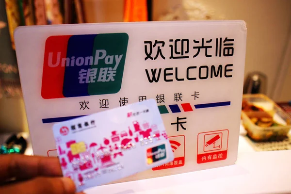 Китайский Клиент Показывает Свою Кредитную Карту Перед Логотипом China Unionpay — стоковое фото