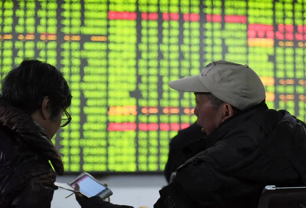 在中国东部浙江省杭州市一家股票经纪公司 中国投资者在电子显示屏前进行了展示股价的讲话 价格上涨为红色 价格下跌为绿色 — 图库照片