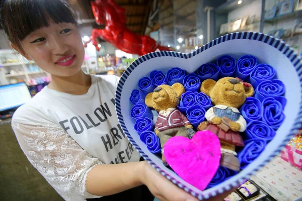 中国のセールスガールは 2015年8月18日 中国河南省海風市の工芸品店で 中国のバレンタインデーとしても知られる 今後のQixiフェスティバルのためにおもちゃのクマで飾られたバラの箱を示しています — ストック写真