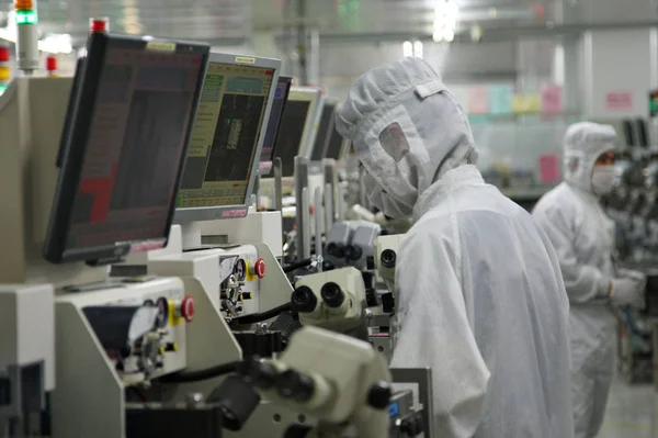 2013年11月21日 中国東部江蘇省南通市の南通富士通マイクロエレクトロニクス社の工場で防塵衣類を着た中国人従業員が作業を行った — ストック写真
