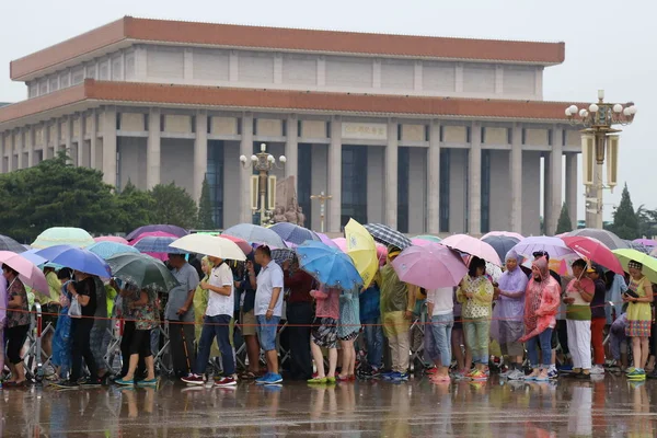 游客们在中国北京天安门广场排队时 用雨伞和雨衣保护自己免受暴雨袭击 — 图库照片