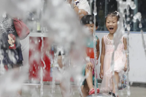 2015年7月13日 中国北部の河北省石家荘市のスコッチャーで冷却するために噴水で水の破片を見ると 若い中国の子供たちは反応します — ストック写真