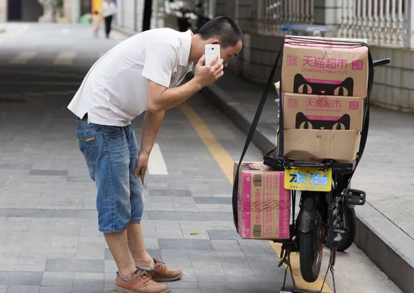 2015年8月18日 中国电子商务巨头阿里巴巴集团 Alibaba Group 在中国东南部福建省厦门市 一名送货员在网上购物Chaoshi Tmall Com 用手机递包裹 — 图库照片