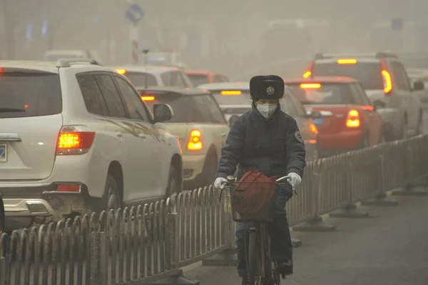 2015年12月1日 中国北京 一名戴着面罩的自行车手在浓雾中骑过马路 — 图库照片