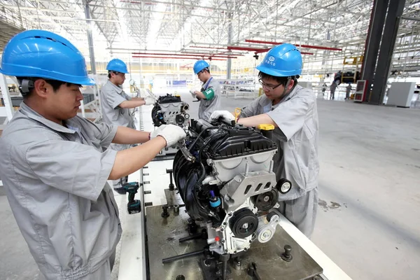 中国の労働者は 中国のホータイモーターの工場で車のエンジンを組み立てます 2014 — ストック写真