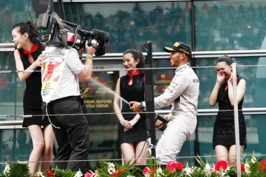 British F1 driver Lewis Hamilton of Mercedes AMG Petronas F1 Team, second right, sprays a hostess champagne to celebrate during the award presentation ceremony of the 2014 Formula 1 Chinese Grand Prix at the Shanghai International Circuit in Shanghai clipart