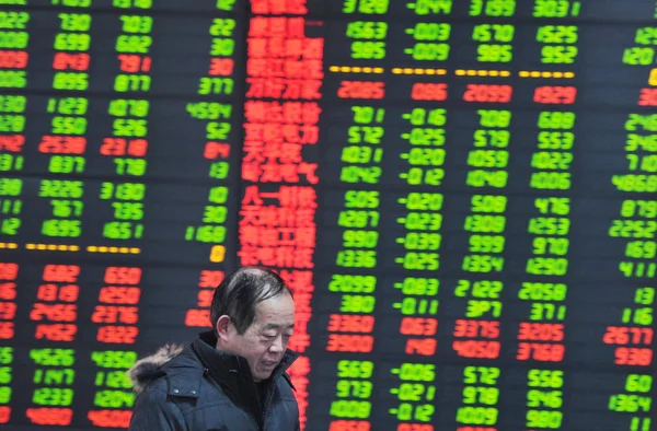 2015年1月19日 在中国东部安徽省阜阳市的一家股票锦绣屋 一位中国投资者走过一个显示股价的屏幕 价格上涨为红色 价格下跌为绿色 — 图库照片