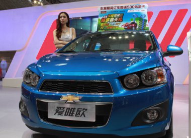  model poses with a Chevrolet Aveo of Shanghai GM, a joint venture between SAIC and General Motors, during an automobile exhibition in Haikou city, south Chinas Hainan province, 22 April 2014 clipart