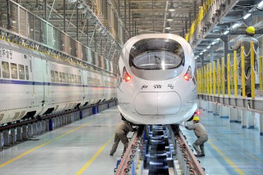 Chinese technicians examine a CRH (China Railway High-speed) bullet train at a maintenance station in Nanjing city, east Chinas Jiangsu province, 14 January 2014 clipart