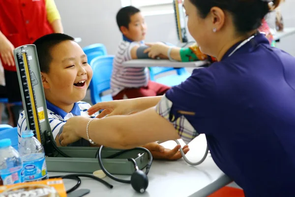 中国の労働者は 上海の学校で身体検査中に肥満の若い学生の血圧を測定します 2014 — ストック写真