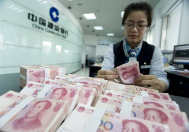 A Chinese employee counts RMB (renminbi) yuan banknotes at a branch of China Construction Bank (CCB) in Haian county, Nantong city, east Chinas Jiangsu province, 10 June 2014 clipart