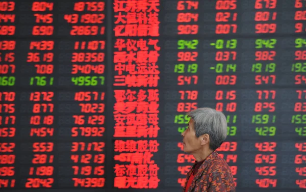 2014年4月8日 在中国东部安徽省阜阳市一家股票经纪公司 一名中国投资者走过显示股价 价格上涨为红色 价格下跌为绿色 的屏幕 — 图库照片