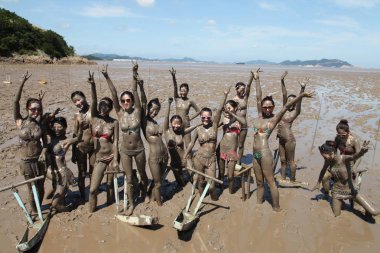 Young Chinese models who get muddy all over pose in the mud on a tidal flat on the Xiushan Island in Daishan county, Zhoushan city, east Chinas Zhejiang province, 22 July 2014 clipart