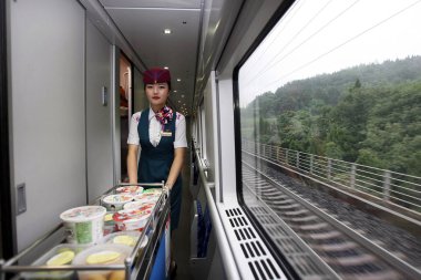 A train attendant serves food on the D628 CRH (China Railway High-speed) bullet train bound for Shanghai at the Chengdu Railway station in Chengdu city, southwest Chinas Sichuan province, 1 July 2014.  clipart