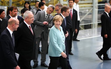 German Chancellor Angela Merkel, center, is accompanied by Volkswagen CEO Martin Winterkorn, second left, Dr. Jochem Heizmann, second right, President and CEO of Volkswagen China, and other officials and executives as they visit the auto plant of FAW clipart