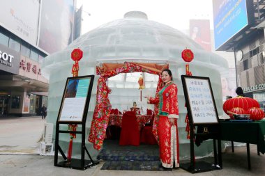 A Chinese waitress poses at the entrance of the hotpot restaurant made of ice blocks on the Taiyuan shopping street in Shenyang city, northeast China's Liaoning province, 20 January 2015 clipart
