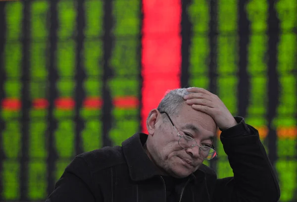 2014 東中国安徽省阜陽市の証券会社の家で 赤の価格上昇 と価格下落のため緑の株式の価格を見て懸念している中国語の投資家 — ストック写真