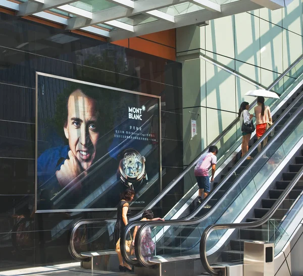 2011年7月9日 在广东省深圳市 行人乘坐自动扶梯 旁边是万宝龙手表的广告 — 图库照片