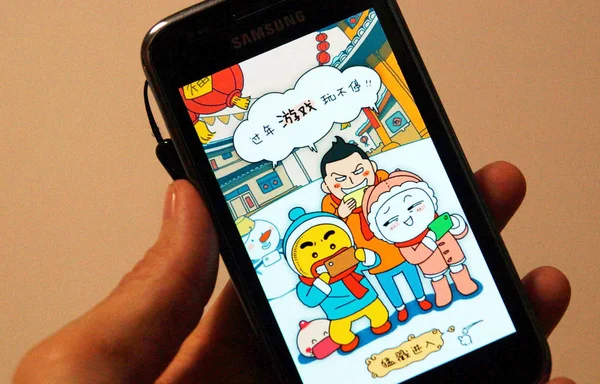 中国の居住者は 2014年1月27日に自分のスマートフォンにモバイルゲームを表示します — ストック写真