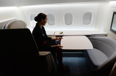 An airhostess of Air France unfolds a table at the new first-class section unveiled by Air France during an exhibition of Air Frances new first-class suite in Shanghai, China, 7 May 2014 clipart